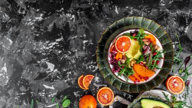 Avokado, hurma, kan portakalı, fındık, ıspanak, roka ve nar içeren sağlıklı vejetaryen salatası, uzun format, üst görünüm.