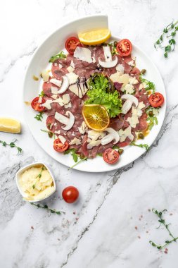 Parmesan kapari ve roka ile sığır eti carpaccio. Soğuk meze. İtalyan mutfağı. dikey görüntü. Üst Manzara. metin için yer.