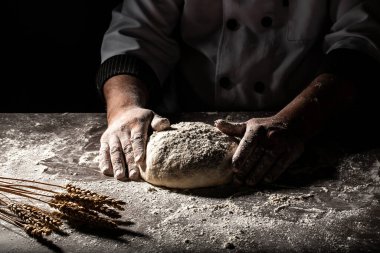 Güzel ve güçlü erkeklerin elleri hamuru yoğurarak ekmek, makarna ya da pizza yaparlar. Bir un bulutu toz gibi uçuşuyor. Yiyecek konsepti