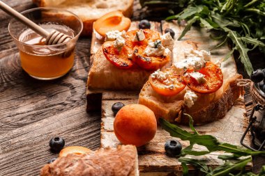 Sağlıklı yaz aperatifleri ya da atıştırmalıklar yumuşak dor peynirli tost, sulu şeftali, hafif arka planda yaban mersini ve bal atıştırmalığı, üst manzara.