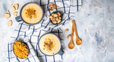 İki kase kremalı mısır çorbası, üstünde fıstık ve kızarmış ekmek, dikey görüntü, vegan mutfağı. Restoran menüsü, diyet, yemek kitabı tarifi..