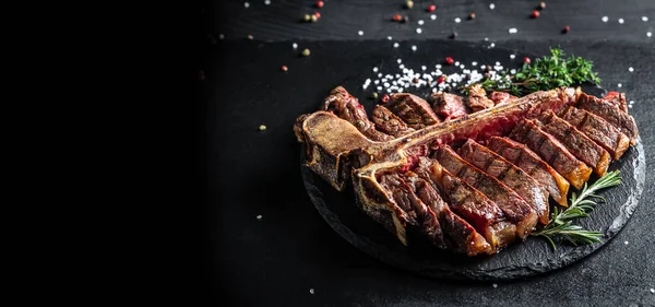 Traditional American barbecue dry aged steak sliced. porterhouse steak sliced as top view on a slate board. banner, catering menu recipe place for text.