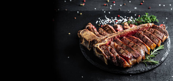 Traditional American barbecue dry aged steak sliced. porterhouse steak sliced as top view on a slate board. banner, catering menu recipe place for text.