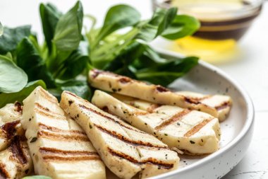 Beyaz tabakta ızgara Halloumi peynirli salata, Kıbrıs peyniri gıcırtısı. Restoran menüsü, diyet, yemek kitabı tarifi üst görünümü.