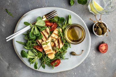 Izgara halloumi peynirli taze salata, domates, kapari, marul ve roka. Ketojenik paleo diyeti. Lezzetli kahvaltı ya da atıştırmalık, temiz yemek, diyet, vejetaryen yemek konsepti. en üstteki görünüm.