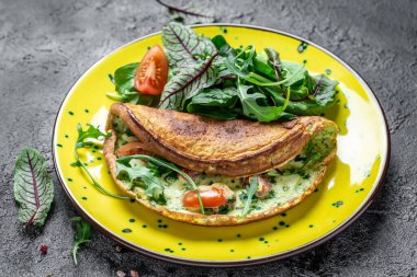Yumurta, peynir ve ıspanak salatasından yapılmış kahvaltı gri arka planda sarı bir tabakta. Ketogenik, keto yemeği. afiş, menü tarifi üst görünümü.
