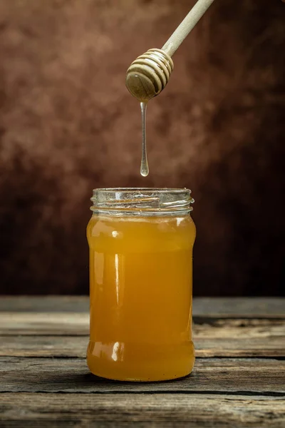 蜂蜜罐和罐子里的木勺 蜜蜂生产新鲜的 健康的蜂蜜 亲爱的背景 养蜂业概念 — 图库照片