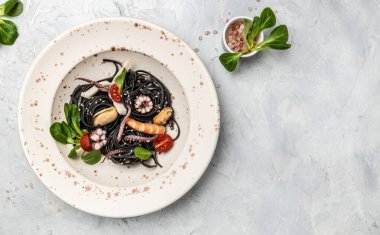 Karidesli siyah spagetti ve hafif arka planda deniz ürünleri makarnası. Siyah deniz ürünleri makarnası. afiş, menü, metin için tarif yeri, üst görünüm.