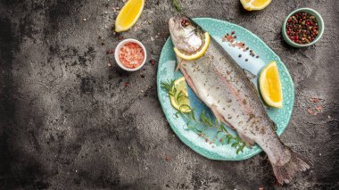 Taze gökkuşağı alabalığı, tuz, biber, limon ve gül. Lezzetli balıklar öğle yemeği için hazırlanıyor. Sağlıklı beslenme konsepti. afiş, menü, metin için tarif yeri, üst görünüm,