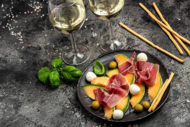 Prosciutto veya jamonlu kavun, mozzarella ve yeşil fesleğen yaprakları, geleneksel İspanyol ve İtalyan aperatifleri toptan Grissini ile servis edilir.,