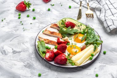 Ketogenik diyet. Yağda yumurta, avokado, çilek, ızgara tavuk fileto, peynir, fındık ve roka düşük karbonhidratlı yüksek yağlı kahvaltı, üst manzara.,