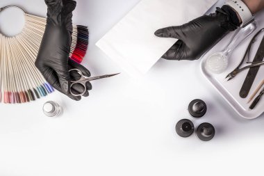 Beyaz arka planda sterilize edilmiş aletler. İlaç ya da güzellik salonu. Kapatın. Eller manikür işleminden önce el işi zarfından manikür aletleri alıyor. Uzun pankart biçimi,