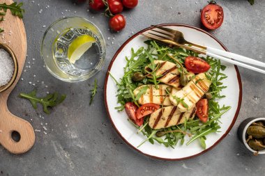 Izgara halloumi peynirli taze salata, domates, kapari, marul ve roka. Ketojenik paleo diyeti. Lezzetli kahvaltı ya da atıştırmalık, temiz yemek, diyet, vejetaryen yemek konsepti. en üstteki görünüm.