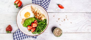 Lezzetli kahvaltı ya da roka ve çilekli tavuk salatası ile atıştırmalık Buda kasesi. Sağlıklı yiyecekler, ketojenik diyet, diyet öğle yemeği konsepti. Keto Paleo diyet menüsü. Üst görünüm.