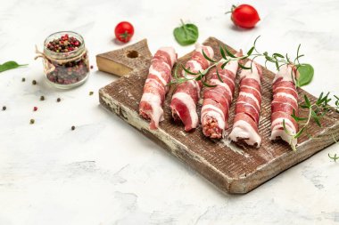 Domuz pastırmasına sarılı kıyma, dökme demir tabakta. Chevapchichi veya Kofta kebabı. Domuz pastırmasına sarılmış soğan ve baharatlı kıymalı çiğ sosis ya da domuz eti.,