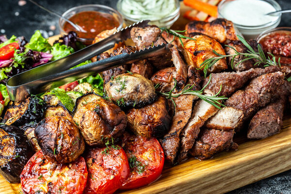 delicious grilled meat with vegetable. Mixed grilled bbq meat with vegetables on wooden platter. Restaurant menu, dieting, cookbook recipe top view,