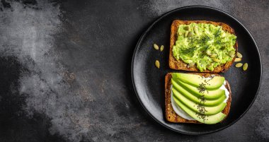 Kahvaltı veya çavdar ekmeği, avokado, roka, kabak ve susam, tuz ve biber dilimlenmiş ile öğle yemeği için sağlıklı avokado kızartır. Vejetaryen sandviç. Bitki temelli diyet. Tüm gıda kavramı.