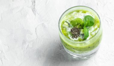 Bardakta Chia pudingi. Sağlıklı kahvaltı. Hafif arka planda kivili chia pudingi. Uzun afiş biçimi. en üstteki görünüm.