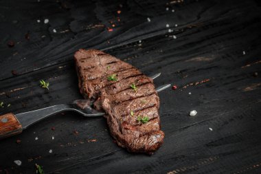 Koyu ahşap arka planda çatallı biftek. afiş, metin için menü tarifi yeri, üst görünüm.