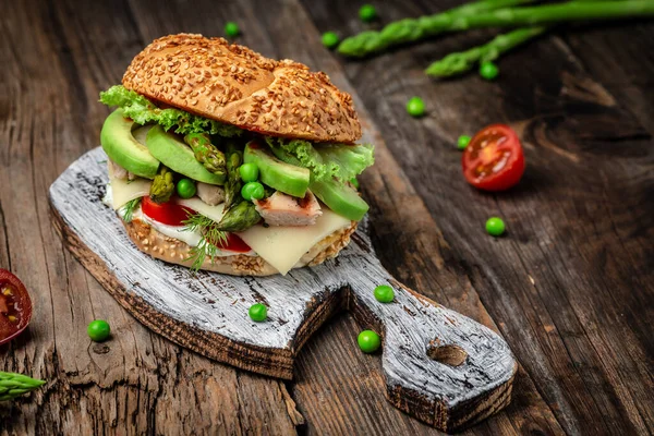 Delicious burgers with chicken fillet, asparagus, avocado, tomatoes, peas, cheese and tartar sauce. fast food and junk food concept.