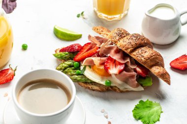 Lezzetli taze kahvaltı, ıspanak ve peynirli ızgara çörek, kuşkonmaz, jambon, jambon, jambon, jambon ve sahanda yumurta. Taze meyve suyu, dengeli diyet. metin için yer, üst görünüm.