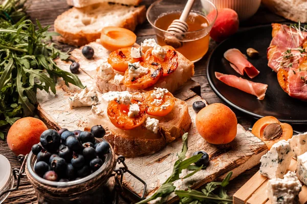 Sağlıklı yaz aperatifleri ya da atıştırmalıkları yumuşak mavi peynirli tost, taze sulu şeftali, yabanmersini ve bal çerezi, üst görünüm.