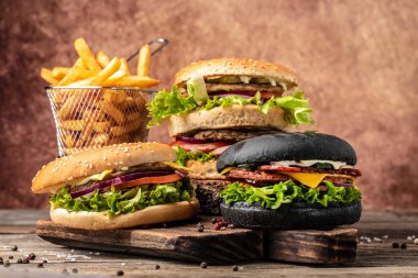 Izgara et, sebze ve ahşap arka planda soslu ev yapımı hamburgerler. Fast food ve abur cubur kavramı,