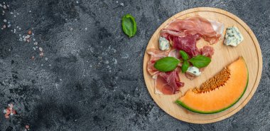 Antipasti. Prosciutto ve fesleğenli taze kavun. İtalyan yemeği. Uzun afiş biçimi. en üstteki görünüm.