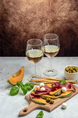 Prosciutto veya jamonlu kavun, mozzarella ve yeşil fesleğen yaprakları, geleneksel İspanyol ve İtalyan aperatifleri toptan Grissini ile servis edilir.,