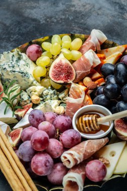 İtalyan atıştırmalıkları ve bardakta şarap olan aperatifler. Peynir, jambon, fındık, meyve, ekmek çubukları. Lezzetli dengeli gıda konsepti.