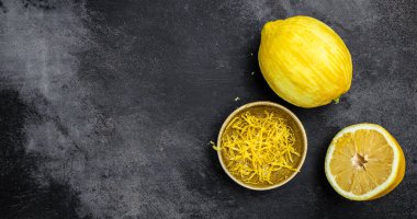 Sarı organik limon, lezzet ve özel alet. Siyah arkaplan, pankart, menü, metin için tarif yeri, üst görünüm üzerindeki rende kabuğu ve limon tadı.