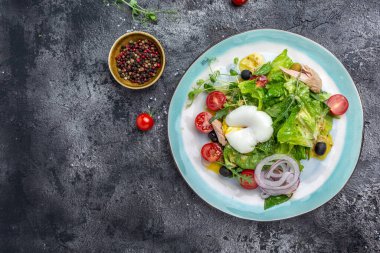 Haşlanmış ton balığı salatası, yumurta, marul, kiraz, domates zeytin ve mısır, koyu taş ya da beton arka planda. Üst Manzara. Boşluğu kopyala.