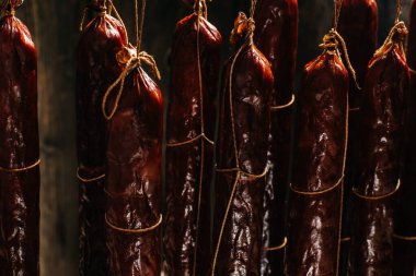 Sigara içme işlemi dumanlı bir dolapta asılı duruyor. Duman bulutları yükselir ve sallanan sosisleri sarar..