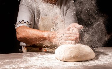 Ekmek, büyükannenin kırışık ellerinde, yakın planda. Büyükanne ekmek hamuru. Büyükanne elinde buğday kulaklı bir parça ekmek tutuyor. Ekmeği olan yaşlı kadın..