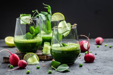 Beton arka planda bir bardakta salatalık yeşili smoothie tazeliyorum. Detox smoothie, taze bezelye, salatalık, turp, ıspanak ve limon..