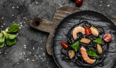 Karidesli ve midyeli siyah spagetti tabağı. Karanlık arka planda. Siyah spagetti. afiş, menü, metin için tarif yeri, üst görünüm,