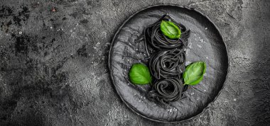 Mürekkep balığı mürekkebi ve yeşil fesleğen yapraklı siyah makarna. Kalamar mürekkepli, keçi buğdaylı makarna. Vejetaryen ya da glütensiz diyet. Restoran menüsü, diyet, yemek kitabı tarifi üst görünümü.