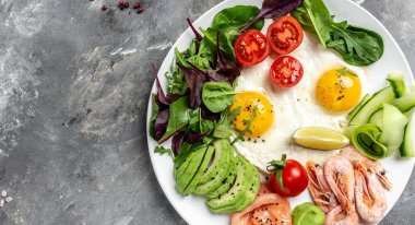 Ketojenik kahvaltı. Keto düşük karbonhidratlı somon, haşlanmış karides, karides, kızarmış yumurta, taze salata, domates, salatalık ve avokado. Üst Manzara. Düşük karbonhidrat diyeti. yüksek yağ diyeti.
