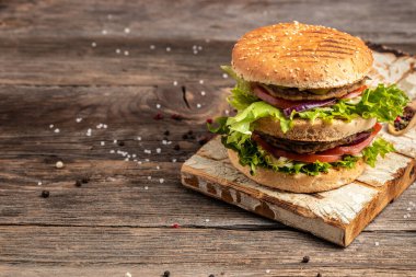 Ev yapımı hamburger, ızgara et, sebze, ahşap arka planda sos. Fast food ve abur cubur kavramı,