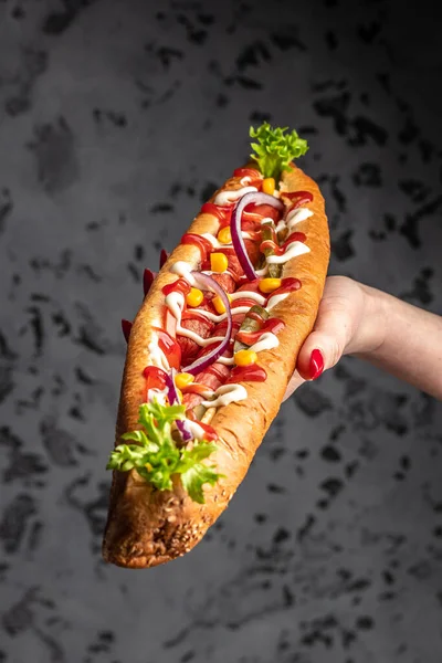 Hot Dog Γαρνιτούρες Στο Χέρι Της Γυναίκας Σκούρο Φόντο Φόντο — Φωτογραφία Αρχείου