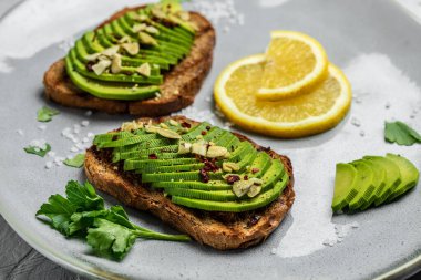 Kahvaltıda sağlıklı avokado tostları ya da öğle yemeğinde çavdar ekmeği, dilimlenmiş avokado, balkabağı tohumu, tuz ve biber. Vejetaryen yemeği. Bitki temelli diyet. Temiz yemek. Üst Manzara. Boşluğu kopyala,