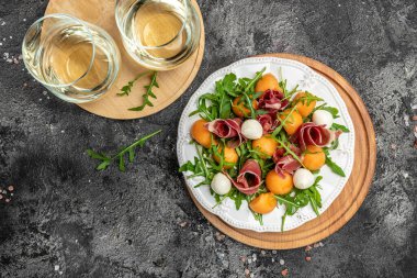 Akdeniz salatası jambon, mozzarella ve yeşil fesleğen yaprakları ve kavun kavunu beyaz masada, geleneksel İspanyol ve İtalyan aperatifi toptan Grissini ile servis edilir..