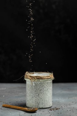 Siyah arka planda laktozsuz yoğurtlu Chia Seed. Chia tohumlu yoğurt sağlıklı süper yiyecek. Cam kavanozdaki süzme peynirli smoothie. dikey görüntü. metin için yer.