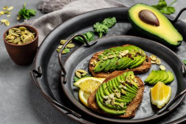 Taze yeşil Avokado sandviç çavdar ekmeği, kabak tohumu, tuz ve biber. Vejetaryen yemeği. Bitki temelli diyet. Temiz yemek. Üst Manzara. Boşluğu kopyala,