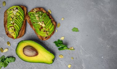 Çavdar ekmekli, balkabaklı, tuzlu ve biberli avokado sandviçi. Vejetaryen yemeği. Bitki temelli diyet. Temiz yemek, uzun afiş formatı. en üstteki görünüm,