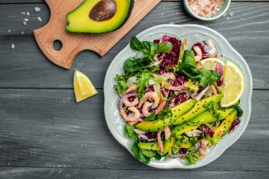 Taze avokado salatası, karides, marul yeşili karışım ve zeytinyağı, limon sosu. Sağlıklı yemek, lezzetli kahvaltı ya da atıştırmalık, temiz yemek, diyet, vejetaryen yemek konsepti. Uzun afiş biçimi. en üstteki görünüm.