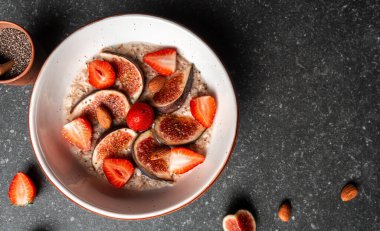 Lezzetli yulaf ezmesi, incir parçalarıyla süslenmiş, bir kasede çilek ve chia tohumları, sağlıklı kahvaltı glüten, laktozsuz, fitness yiyeceği. Uzun pankart biçimi, üst görünüm.