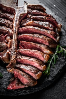 Bir parça pişmiş T-bone ya da yıllanmış wagyu bifteği ızgara biftek ve taş tahtada servis edilmiş baharatlar. dikey görüntü. metin için yer,