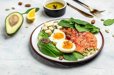 Ketogenik diyet kahvaltısı. somon, avokado, peynir, yumurta, ıspanak ve fındık. Sağlıklı yağlar, kilo vermek için temiz yiyecekler. afiş, menü, metin için tarif yeri, üst görünüm,