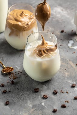 Dalgona kahvesi ya da çırpılmış Kore kahvesi hazır kahve ya da kremalı espresso tozu. Donmuş bir hareketle kahve dolduruyorum. dikey görüntü. Üst Manzara. metin için yer,